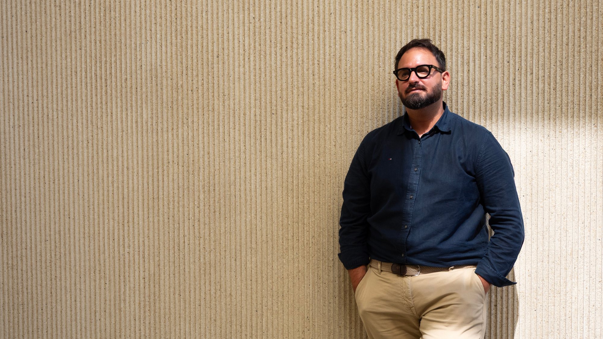 David Quattrini, naturopathe, devant un mur cannelé beige